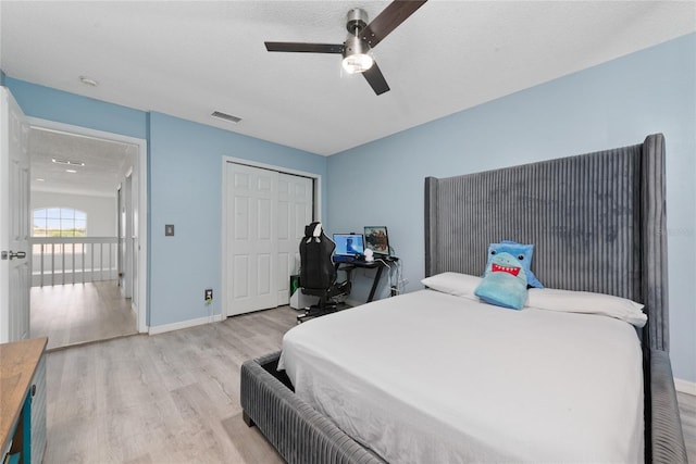 bedroom featuring ceiling fan, light hardwood / wood-style flooring, a closet, and a textured ceiling