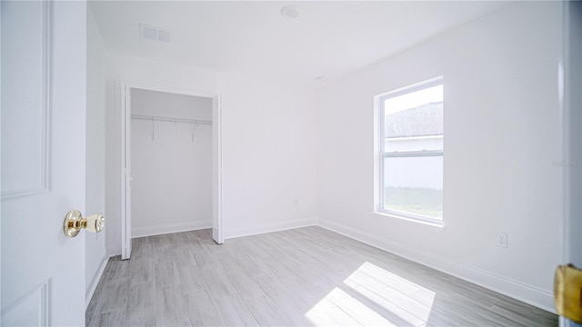 unfurnished bedroom with light wood finished floors, visible vents, a closet, and baseboards