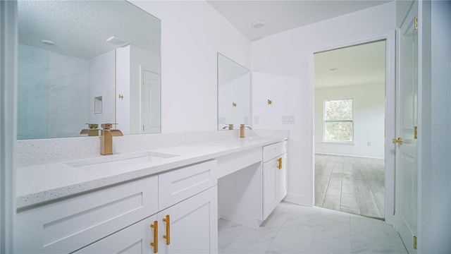 bathroom with a sink, baseboards, marble finish floor, and double vanity