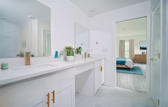 ensuite bathroom featuring double vanity, connected bathroom, marble finish floor, and a sink