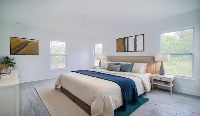 bedroom with multiple windows and hardwood / wood-style flooring