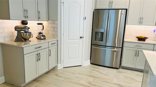 13706 Werrington Dr, Winter Garden, FL 34787 - kitchen featuring light stone countertops, stainless steel refrigerator with ice dispenser, light wood-style floors, and tasteful backsplash