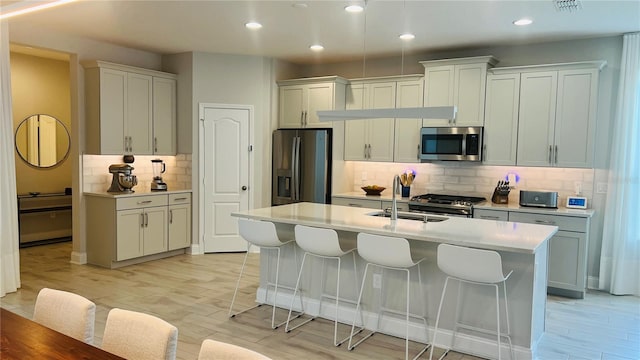 kitchen featuring a center island with sink, light hardwood / wood-style floors, white cabinetry, and stainless steel appliances