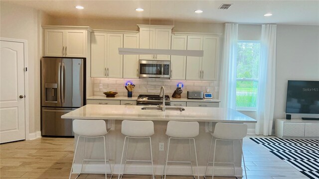 kitchen featuring a center island with sink, white cabinetry, sink, and stainless steel appliances