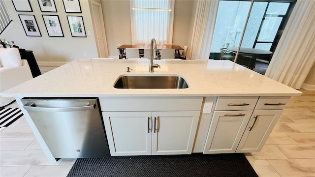 kitchen featuring white cabinets, dishwasher, light stone countertops, and sink