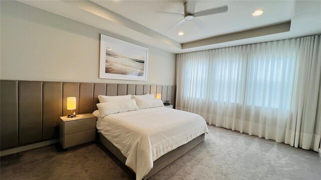 bedroom with carpet, a tray ceiling, and ceiling fan