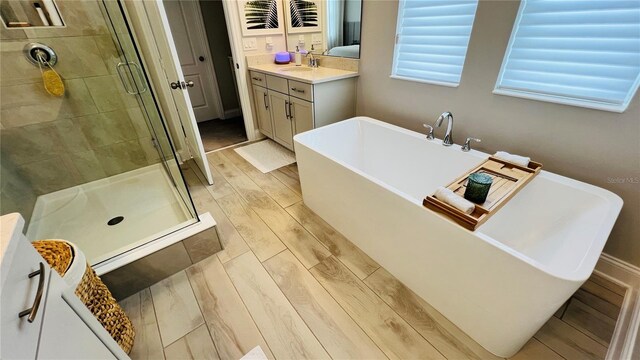 bathroom featuring hardwood / wood-style flooring, vanity, and separate shower and tub