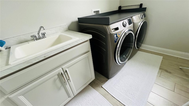 laundry room with separate washer and dryer, cabinets, light wood-type flooring, and sink