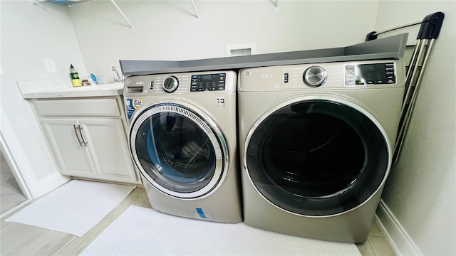 laundry area with washing machine and clothes dryer and cabinets