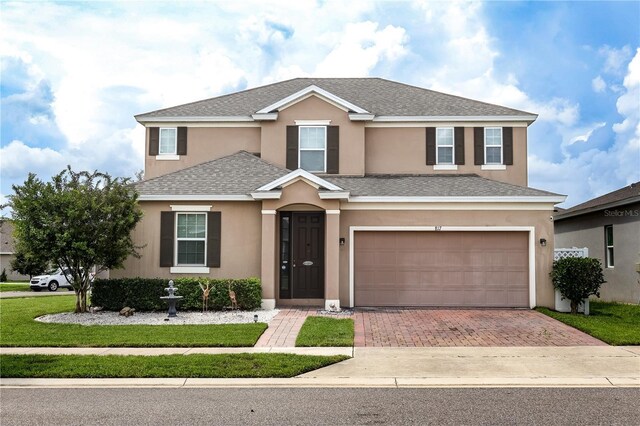 front facade with a garage and a front lawn