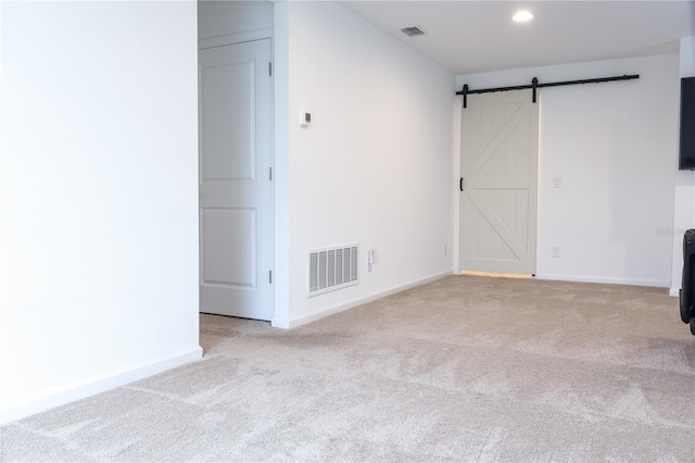 carpeted spare room featuring a barn door