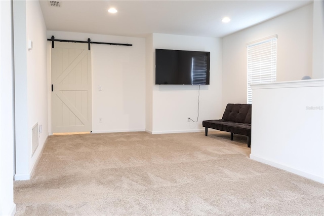 unfurnished room featuring light colored carpet and a barn door