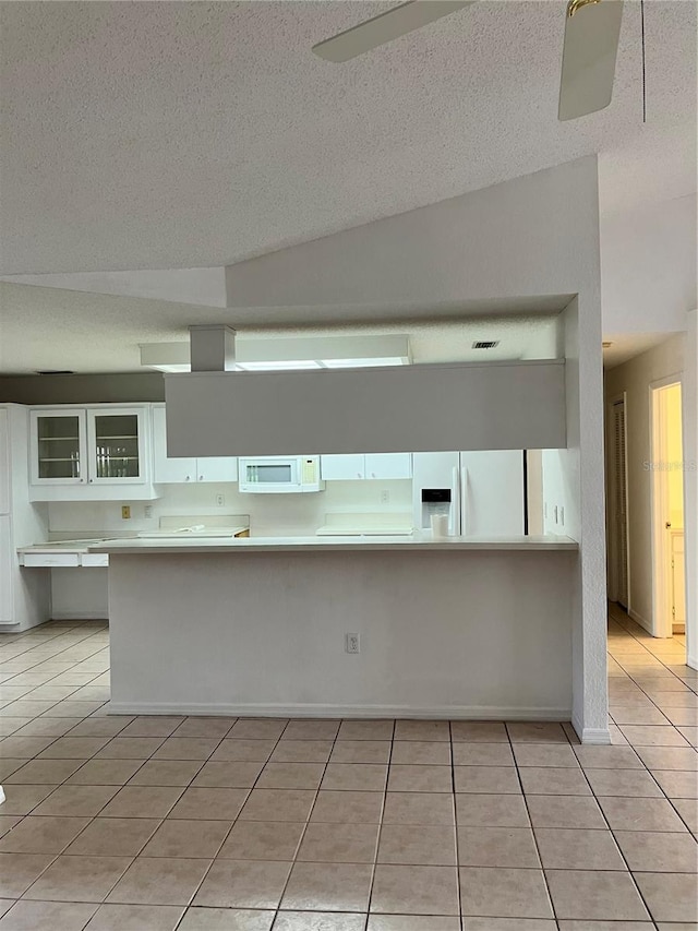 kitchen with light tile patterned floors, white appliances, white cabinetry, and lofted ceiling