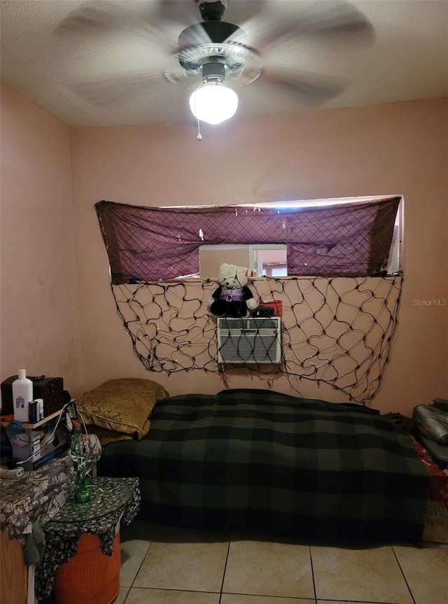 bedroom with a textured ceiling, light tile patterned floors, and ceiling fan