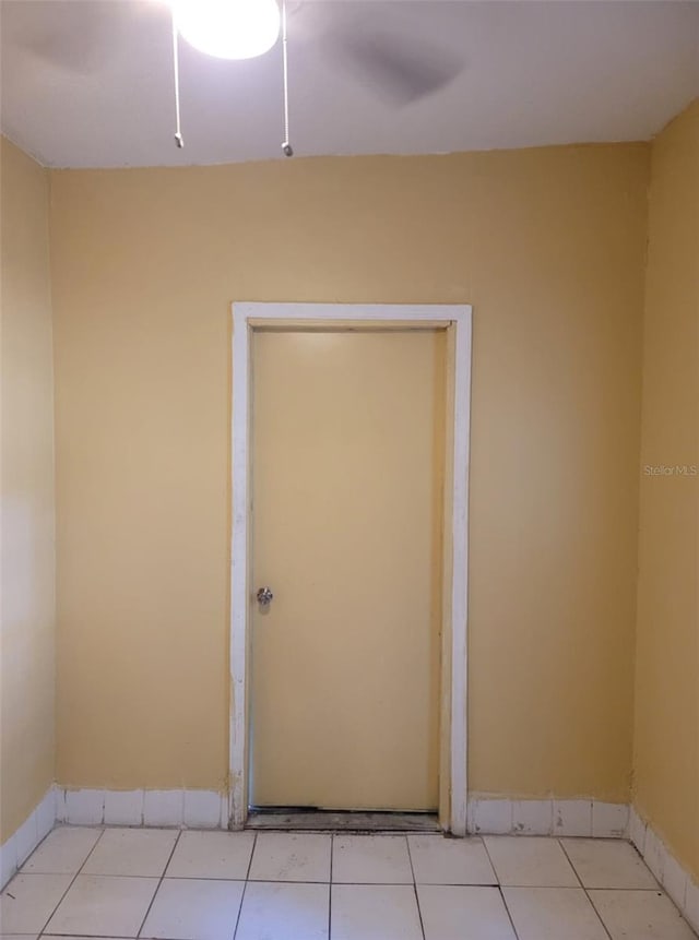 tiled spare room featuring ceiling fan