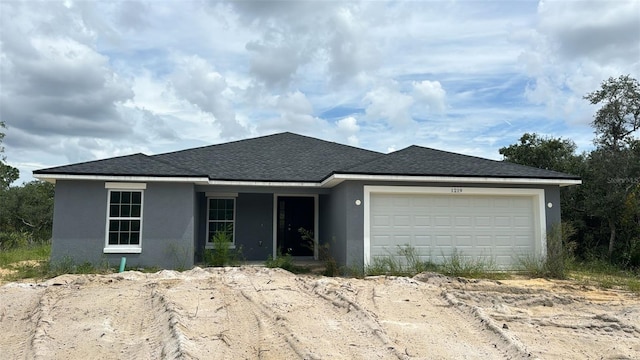 ranch-style home with a shingled roof, an attached garage, driveway, and stucco siding