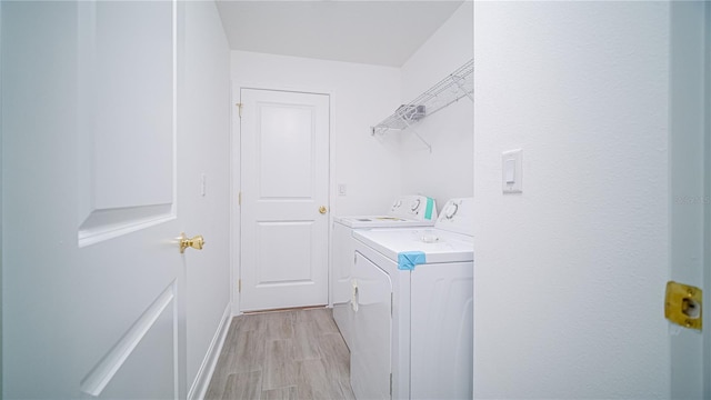 washroom featuring baseboards, independent washer and dryer, light wood-style flooring, and laundry area