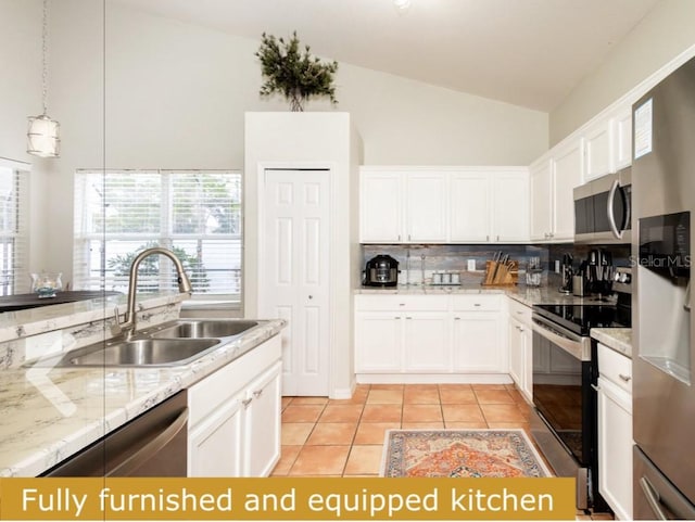 kitchen featuring stainless steel appliances, sink, vaulted ceiling, decorative light fixtures, and white cabinetry