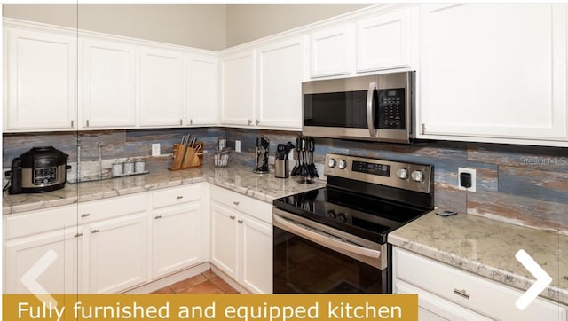 kitchen featuring appliances with stainless steel finishes, white cabinetry, tasteful backsplash, and light tile patterned floors