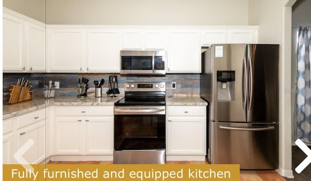 kitchen featuring white cabinetry, light stone counters, stainless steel appliances, and tasteful backsplash