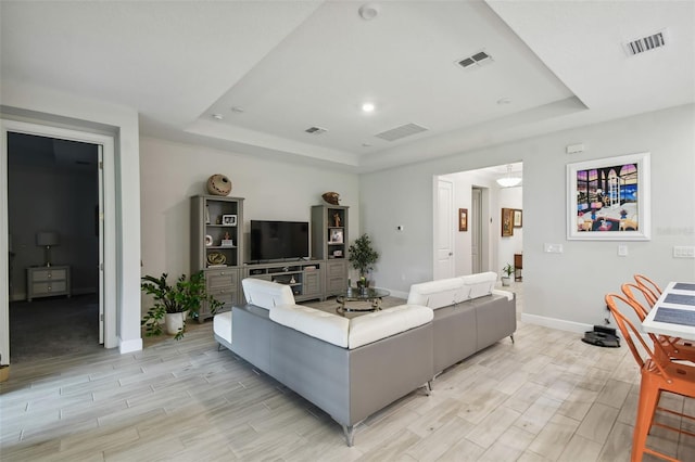 living room featuring a raised ceiling and light hardwood / wood-style flooring