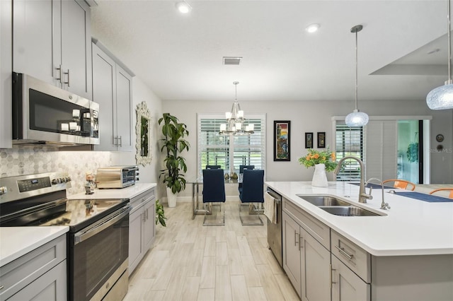 kitchen with plenty of natural light, stainless steel appliances, sink, and hanging light fixtures