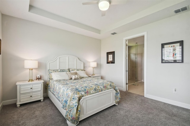 carpeted bedroom with ensuite bath, a raised ceiling, and ceiling fan