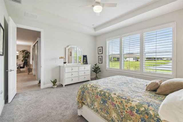 carpeted bedroom featuring ceiling fan and a tray ceiling