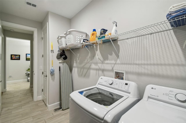 laundry room with light wood-type flooring and separate washer and dryer