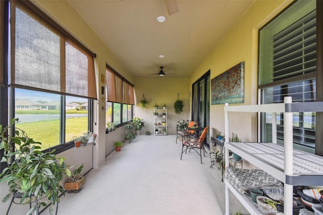 sunroom featuring a water view and ceiling fan