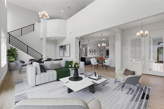 living room featuring an inviting chandelier, a towering ceiling, and light hardwood / wood-style flooring