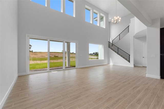 unfurnished living room with a chandelier and light wood-type flooring