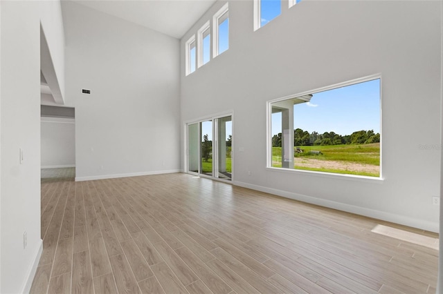 unfurnished living room featuring a high ceiling and light hardwood / wood-style flooring