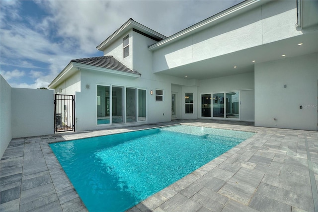 107 Hampton Loop, Davenport, FL 33837 - back of house with a gate, stucco siding, an outdoor pool, a patio, and a tile roof