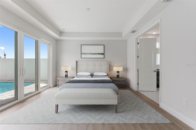 107 Hampton Loop, Davenport, FL 33837 - bedroom featuring access to outside, wood finished floors, baseboards, and a tray ceiling