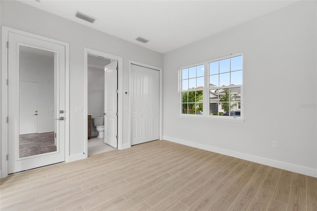 107 Hampton Loop, Davenport, FL 33837 - unfurnished bedroom featuring light wood-style floors, baseboards, connected bathroom, and a closet