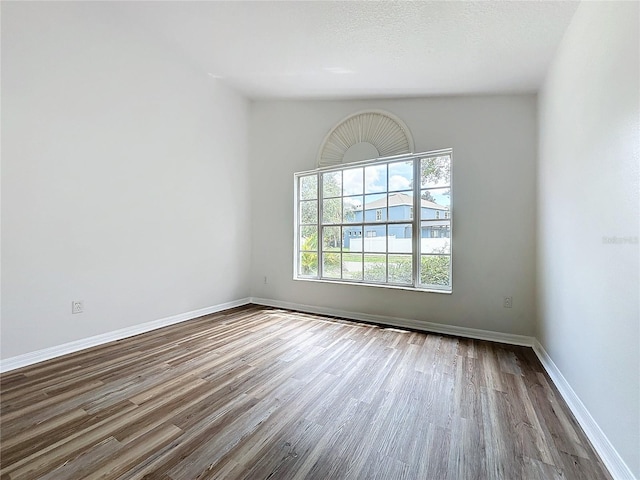 spare room featuring baseboards, a textured ceiling, and wood finished floors