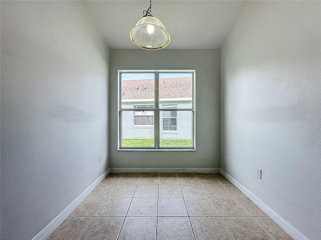 spare room with light tile patterned flooring, a textured wall, baseboards, and a textured ceiling