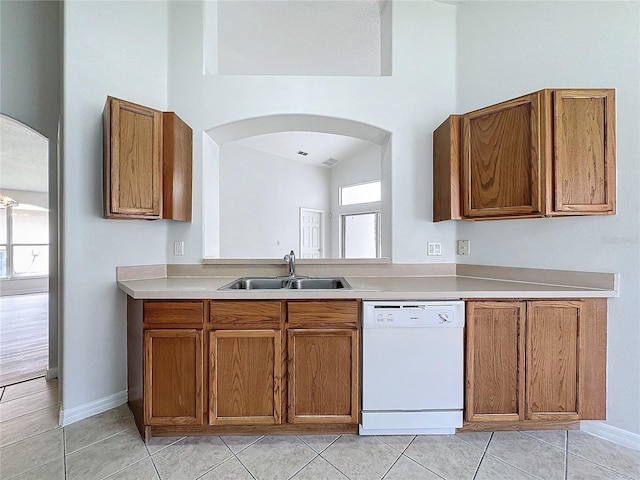 kitchen with brown cabinets, dishwasher, light countertops, and a sink