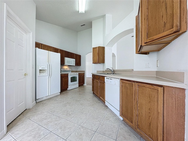 kitchen with visible vents, white appliances, arched walkways, light tile patterned flooring, and light countertops