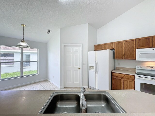 kitchen with white appliances, brown cabinetry, lofted ceiling, and a sink