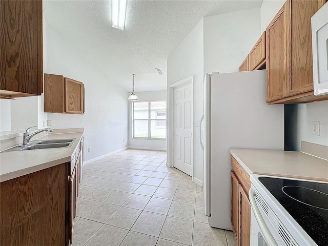 kitchen with white microwave, brown cabinets, light tile patterned flooring, a textured ceiling, and a sink