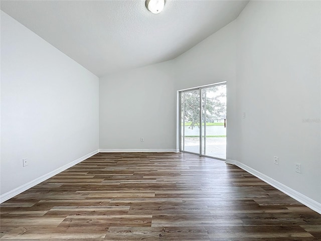 empty room featuring vaulted ceiling, wood finished floors, and baseboards