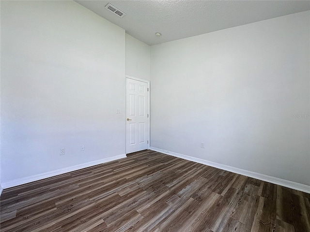 unfurnished room featuring baseboards, visible vents, dark wood-style flooring, and a textured ceiling