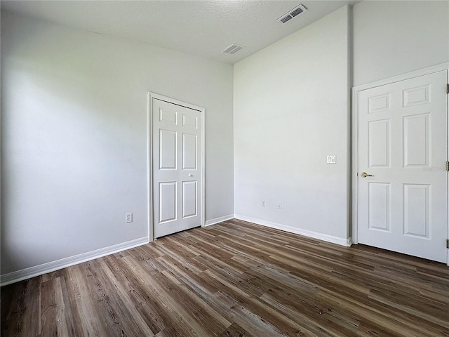 unfurnished bedroom featuring dark wood-type flooring, baseboards, and visible vents