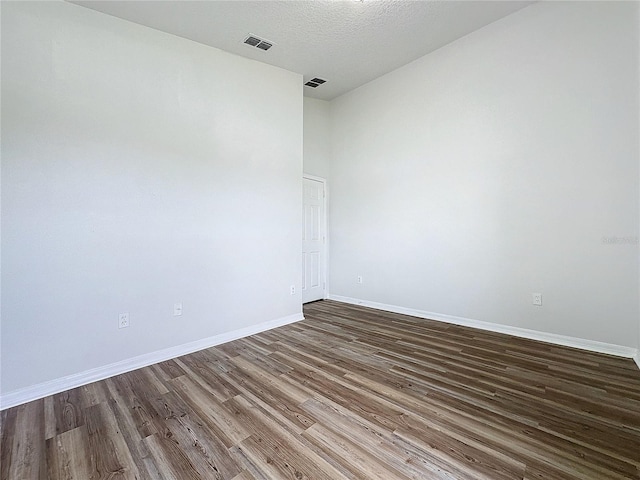 unfurnished room featuring visible vents, baseboards, a textured ceiling, and wood finished floors