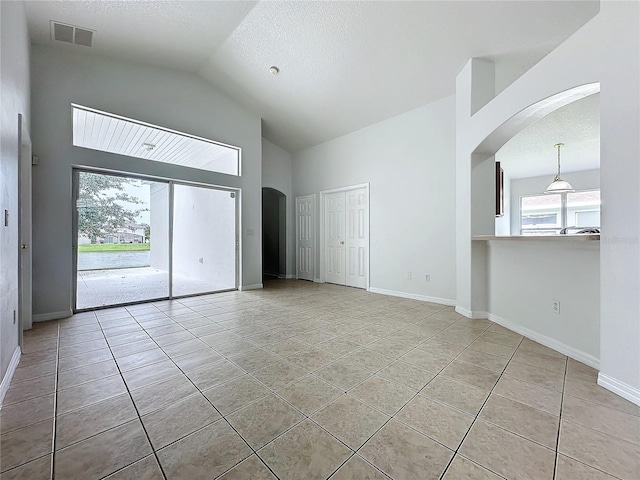 spare room with light tile patterned flooring, visible vents, arched walkways, and baseboards