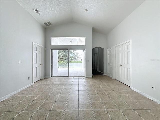 unfurnished room featuring light tile patterned floors, arched walkways, visible vents, and baseboards