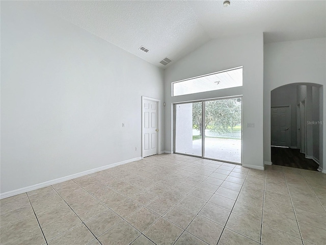 spare room with light tile patterned floors, visible vents, arched walkways, and baseboards