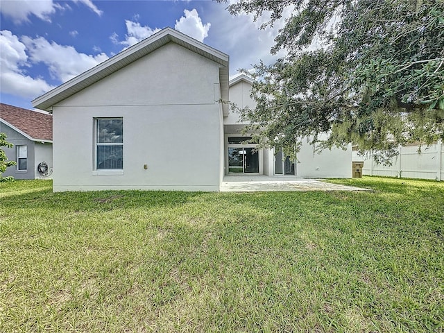 rear view of property featuring a patio area, stucco siding, a yard, and fence